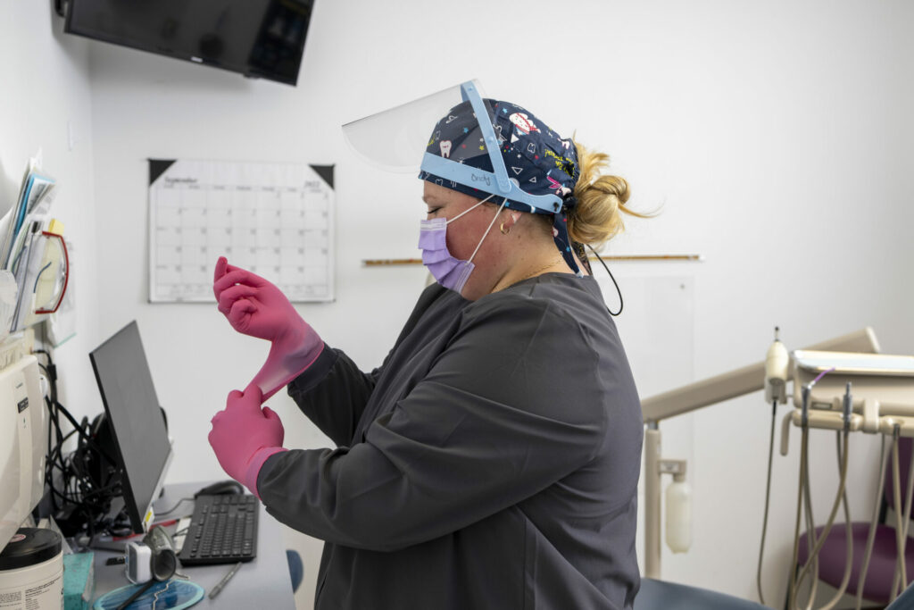 A dental hygienist put on pink gloves to perform dental services at a Hackley Community care dental suite.